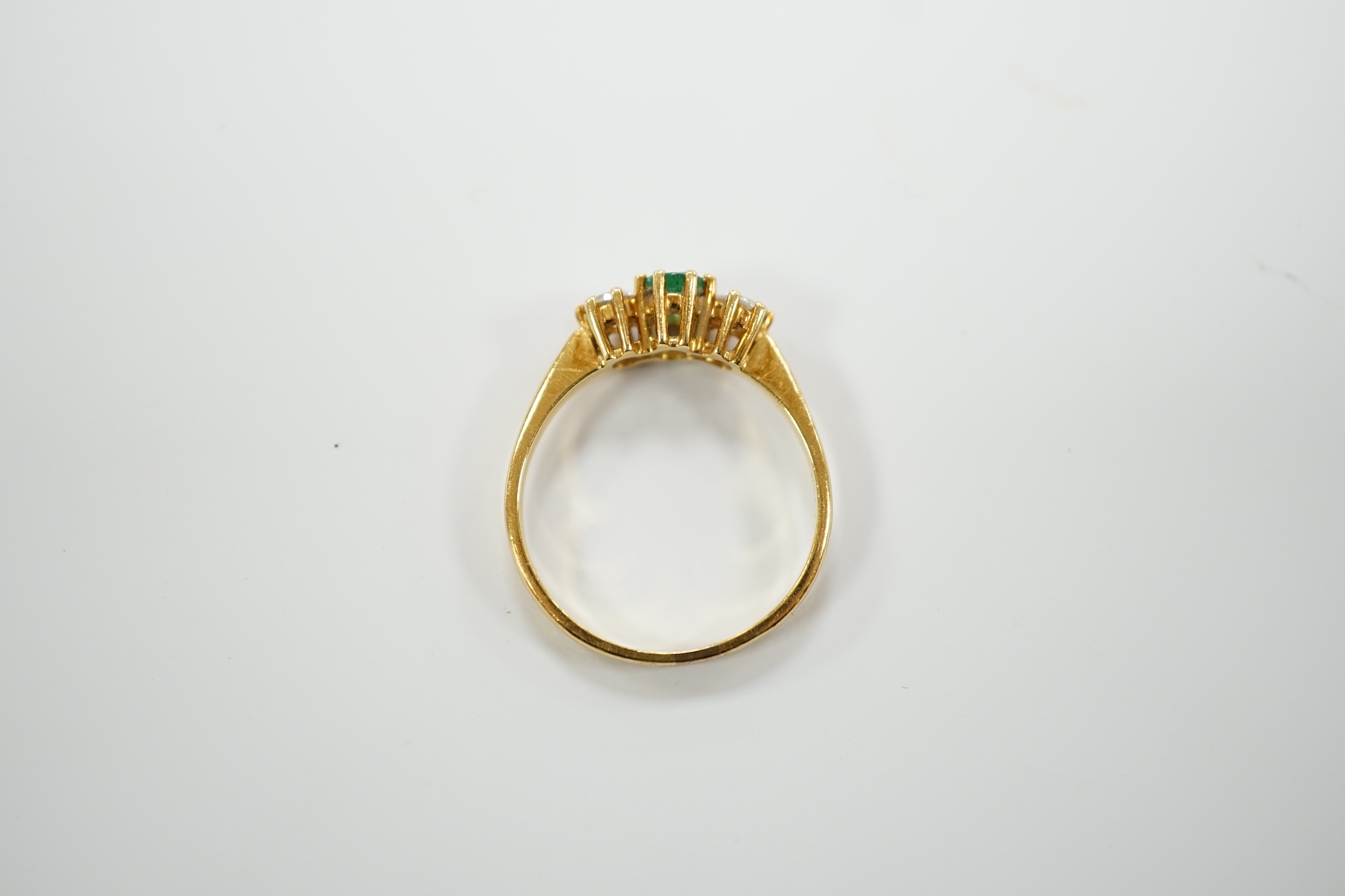 A modern 18ct gold, emerald and diamond set three stone ring, size P, gross weight 3.2 grams.